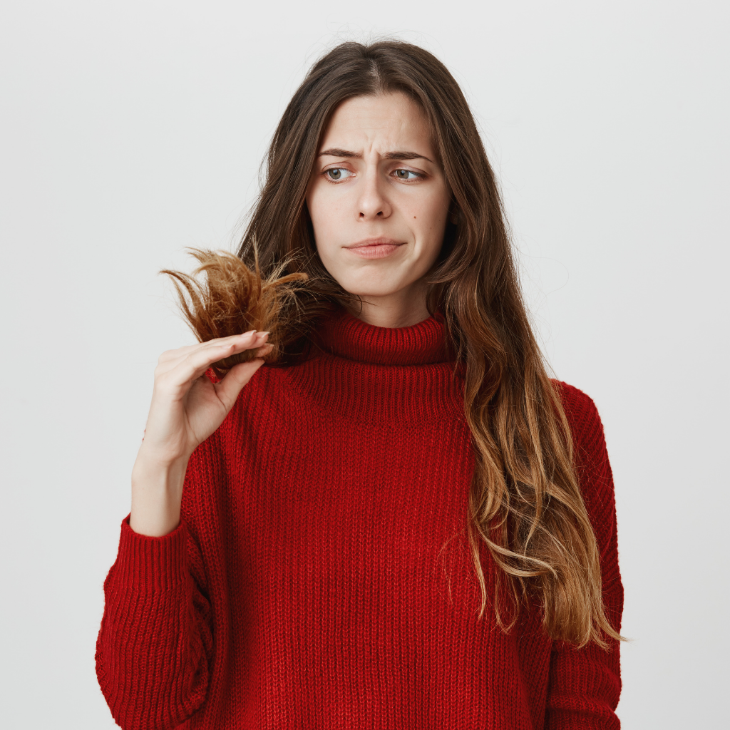Mulher olhando para o próprio cabelo e pensando se precisa fazer uma reconstrução capilar.