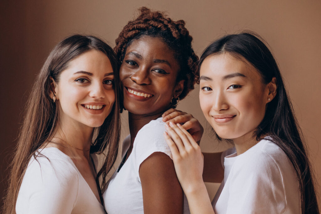 Imagem com três mulheres, da esquerda para a direita: uma mulher branca, uma mulher negra e uma mulher asiática